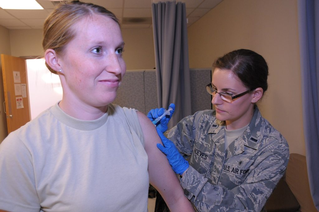 A doctor holding a vaccine vial beside a child health record